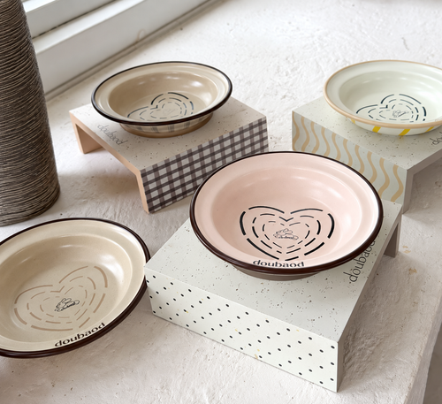MeAura pastel cat feeding bowls with raised stands displayed beside a window